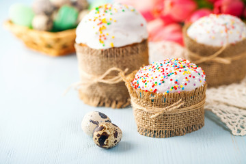 Easter orthodox sweet cakes, kulich and colorful quail eggs with pink tulips. Holidays Easter concept. Selective focus