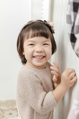 Little pretty Asian girl standing in a normal indoor life background.