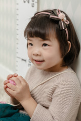 Little pretty Asian girl standing in a normal indoor life background.