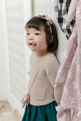 Little pretty Asian girl standing in a normal indoor life background.