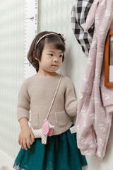 Little pretty Asian girl standing in a normal indoor life background.