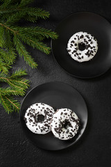 Donuts with white icing and chocolate chips in a black plate on the black kitchen table. Doughnuts on a plate. Delicious pastries. Top view with space for text