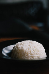 Steamed rice on black plate. Creative minimalism, dark food photography concept. Copy space