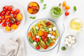 healthy fusilli pasta with pesto sauce, roasted tomatoes, mozzarella