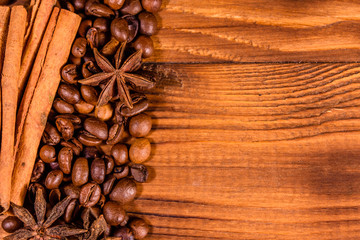 Pile of the coffee beans, star anise and cinnamon sticks on wooden table. Top view