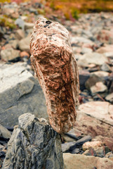 light natural cobblestone stands vertically in delicate balance on another stone