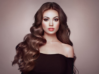 Brunette Girl with Long Healthy and Shiny Curly Hair. Care and Beauty. Beautiful Model Woman with...