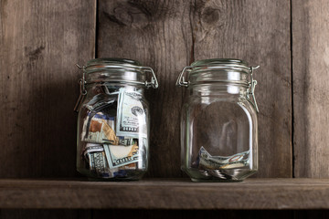 Two piggy banks, with different amounts of money and space for text, stand on a wooden bookshelf.