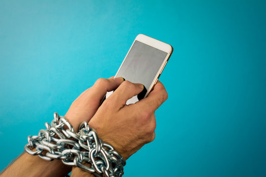 Mobile phone chained to the hands of a man. Concept of  internet or social media addiction