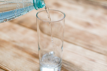 Sparkling water is poured into a glass on a wooden background.