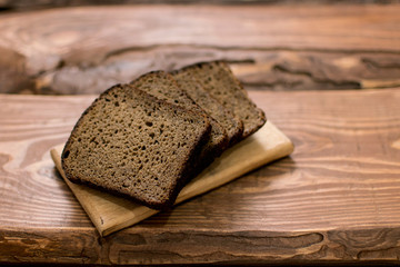 Slices of black bread on a wooden background.