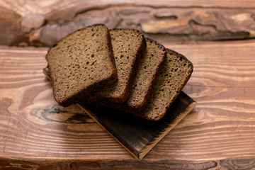 Slices of black bread on a wooden background.