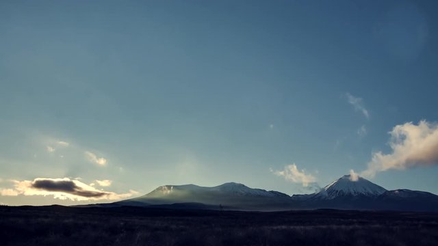Tongariro National Park, New Zealand during sunrise. Beautiful snowy peaks of volcanos and dramatic clouds forming on frosty morning. Timelapse video.