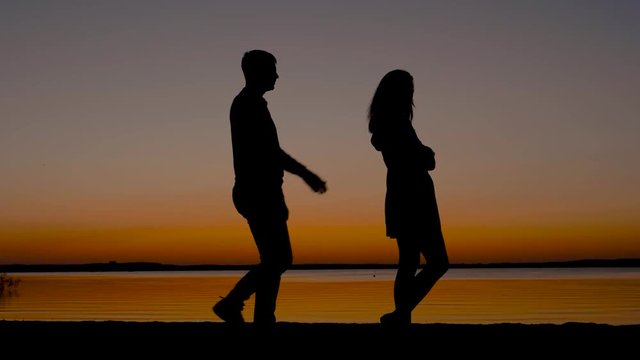 Silhouettes Of Men And Women Quarrel At Sunset On The Seashore