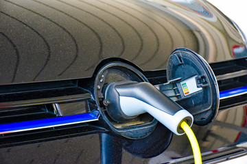 A electric vehicle is charged at a charging station. The charging plug is plugged into the socket...