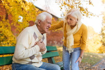 Senior man experiencing chest pain while senior woman comforts him