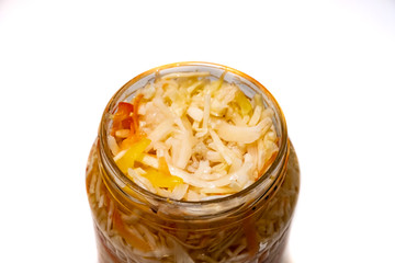 Preserved cabbage and red paprika salad in glass jar on a white background
