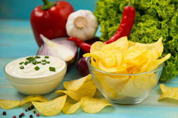 Potato chips in bowl on a blue wooden background