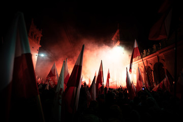 People carry Polish flags and burn flares as they walk across the Poniatowski Bridge during a march marking the 100th anniversary of Polish independence in Warsaw, Poland November 11, 2018.  - obrazy, fototapety, plakaty