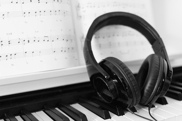 Close up of headphone on a piano with music note in the background