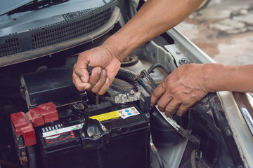 Car mechanic working Install battery with wrench in garage. Repair service.