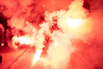 People carry Polish flags and burn flares as they walk across the Poniatowski Bridge during a march marking the 100th anniversary of Polish independence in Warsaw, Poland November 11, 2018. 