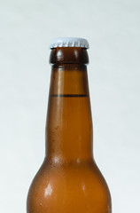 Cold beer bottle without label on wooden table back-lit isolated on white background