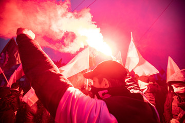 People carry Polish flags and burn flares as they walk across the Poniatowski Bridge during a march marking the 100th anniversary of Polish independence in Warsaw, Poland November 11, 2018.  - obrazy, fototapety, plakaty