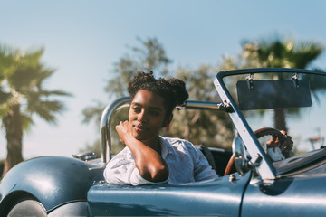 Black woman driving a vintage convertible car