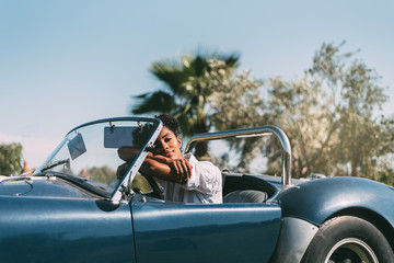 Black woman driving a vintage convertible car
