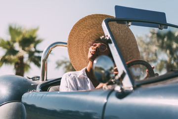 Black woman driving a vintage convertible car