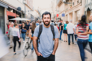 Young and attractive man touring the city of Bordeaux in France. Standing on streets full of people. Lifestyle. Travel photography.
