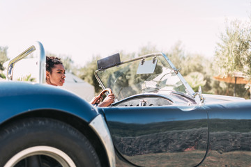 Obraz na płótnie Canvas Black woman driving a vintage convertible car