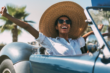 Black woman driving a vintage convertible car