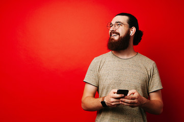 Happy man with beard using phone over red background with copyspace