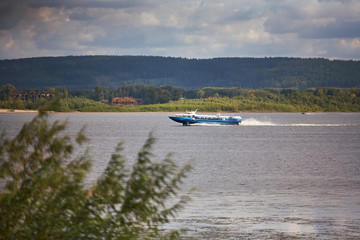 Obraz premium Boat on the background of cloudy sky and the shore with trees.