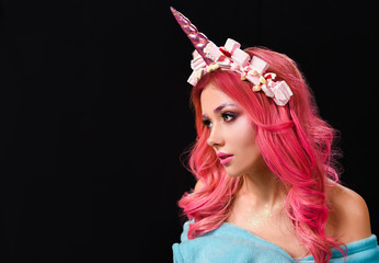 The Unicorn Girl. Young beautiful girl in the image of unicorn with pink hair and stylish make-up, copy space.