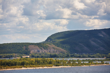 River against a cloudy sky with clouds and forest.