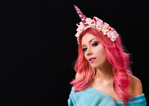 The Unicorn Girl. Young beautiful girl in the image of unicorn with pink hair and stylish make-up, copy space.