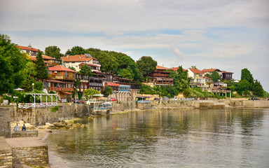 Fototapeta na wymiar View of the seaside promenade with small cozy houses and water Bulgaria old Nessebar