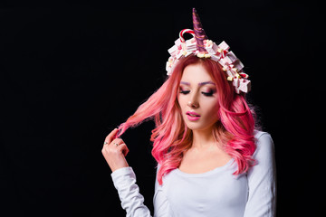 The Unicorn Girl. Young beautiful girl in the image of unicorn with pink hair and stylish make-up, copy space.