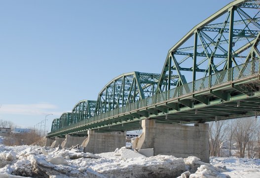 green trass bridge over a frozen river