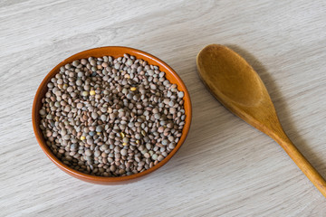 Lentils in a bowl and wooden spoon on a wooden background