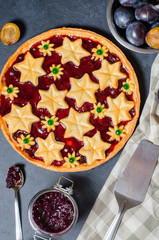Round homemade cake with plum jam, plums. Dark background. Vertical photo. Flat Lay