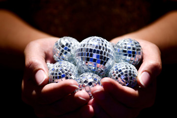 Close up of cupped hands holding disco balls