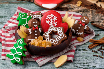 Gingerbread mitten, little man, snowflakes, christmas trees in a brown wooden plate on a striped napkin on a green wooden background. close up. space