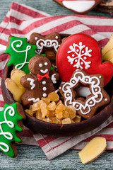 Gingerbread mitten, little man, snowflakes, christmas trees in a brown wooden plate on a striped napkin on a green wooden background. close up. spacep. space