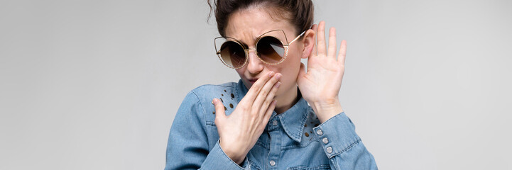 Young brunette girl in black glasses. Cat glasses. The hair is gathered in a bun. The girl...
