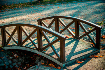 Beautiful wooden arched bridge over the river the flows in a park in a city