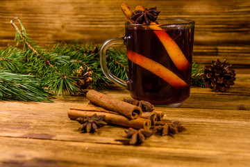 Cup of mulled wine with cinnamon and fir tree branches on wooden table